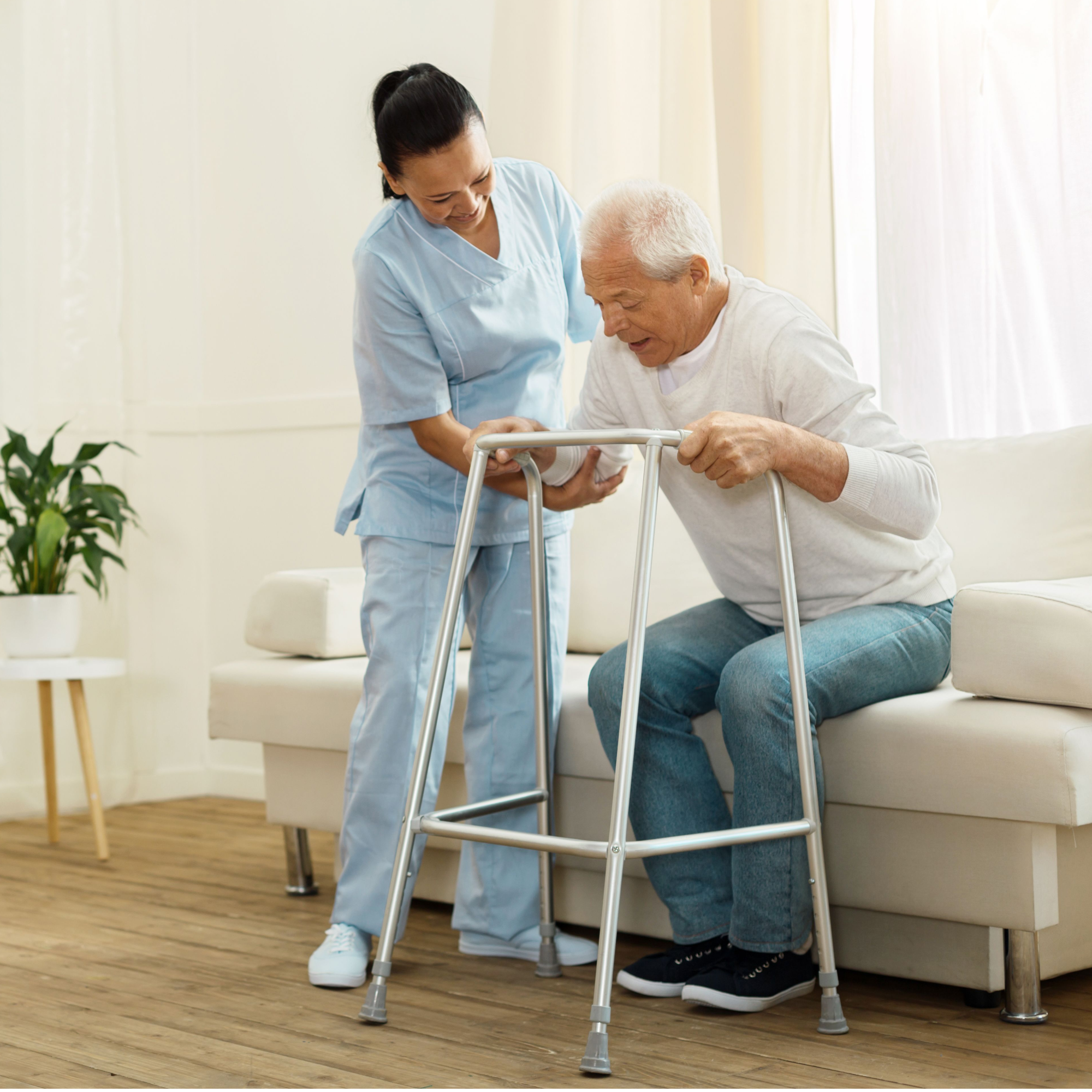 An in home caregiver assists a man struggling to get up from a sitting position